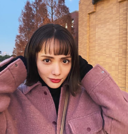 伊藤ニーナさんがピンクっぽいコートを着て外での写真