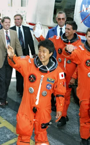 向井千秋さんが宇宙服を着て手を振っている画像